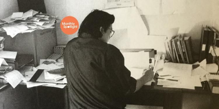 Black and white photo of Kazuo Ishiguro writing at his desk.
